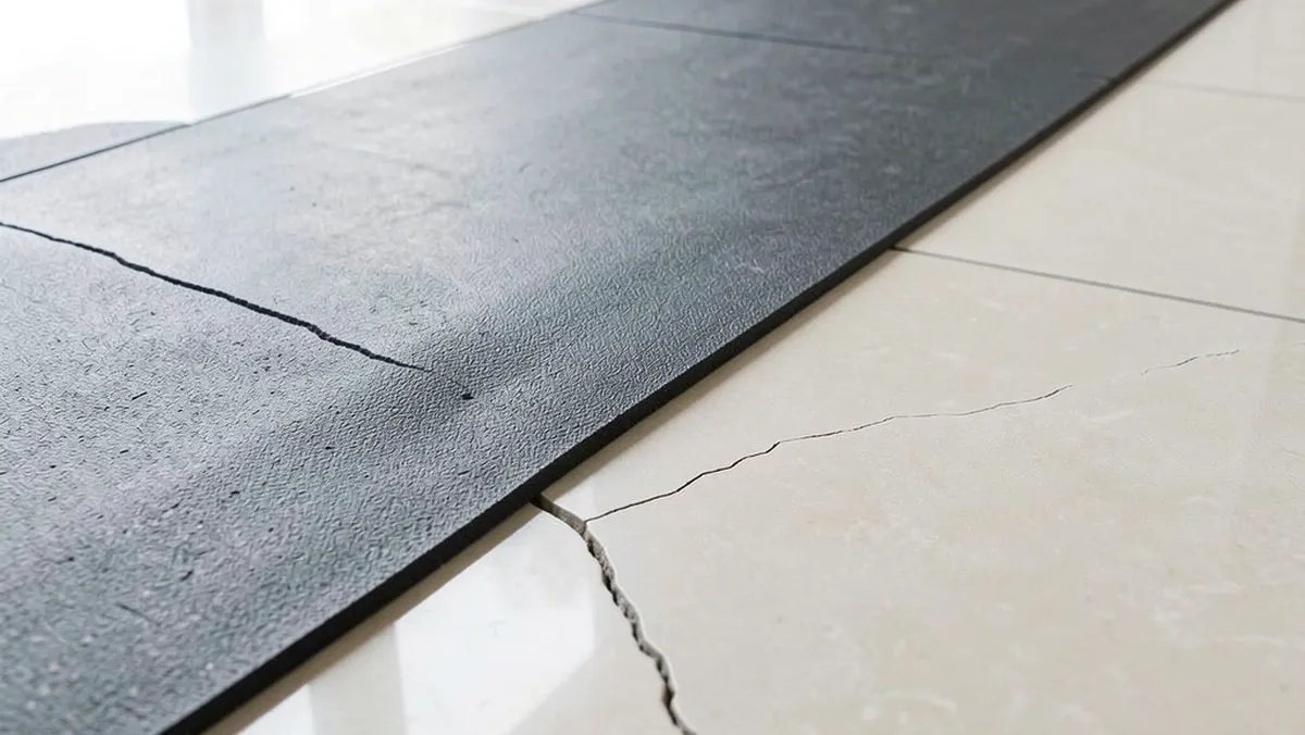 Ceramic tile with hairline crack near walking pad on rubber mat
